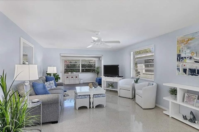 living room with ceiling fan, baseboards, and light speckled floor