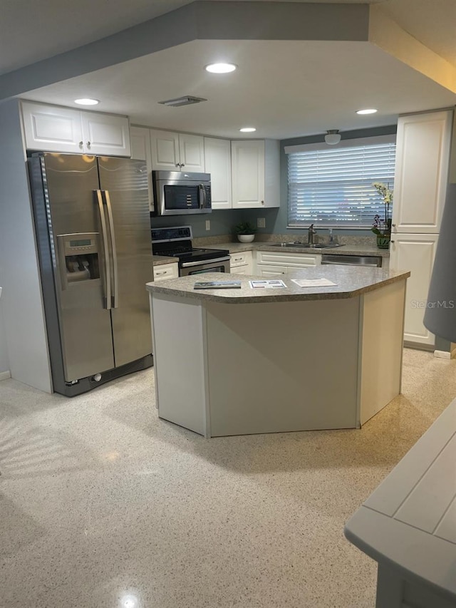 kitchen featuring appliances with stainless steel finishes, a sink, visible vents, and white cabinets