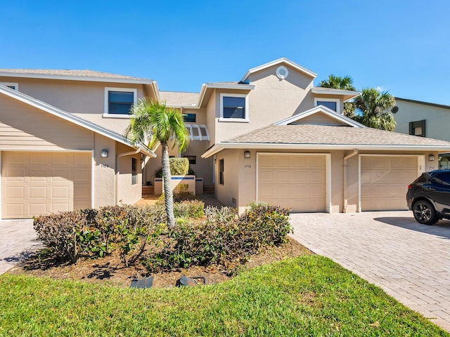 multi unit property with a shingled roof, decorative driveway, and stucco siding