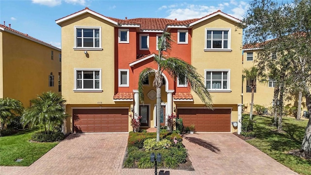 multi unit property with a garage, a tile roof, and stucco siding