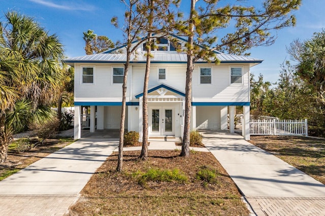 coastal inspired home featuring driveway, metal roof, a carport, and french doors