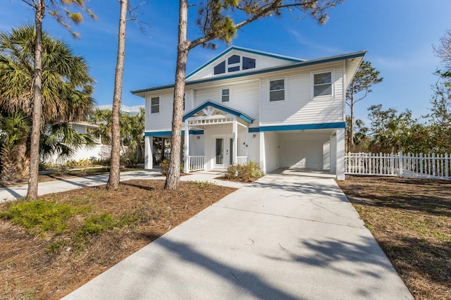 raised beach house with a carport, concrete driveway, and fence