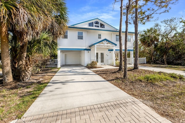 view of front facade featuring concrete driveway, french doors, and an attached garage