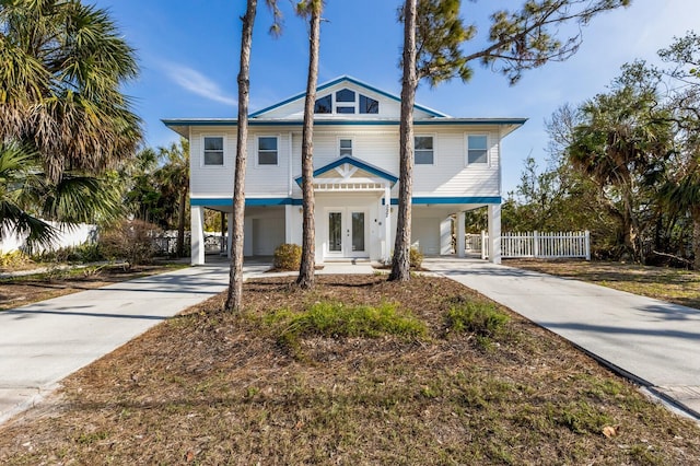 coastal inspired home with driveway, a carport, and french doors