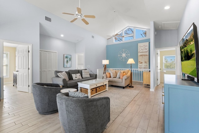 living area featuring high vaulted ceiling, light wood-type flooring, a healthy amount of sunlight, and visible vents