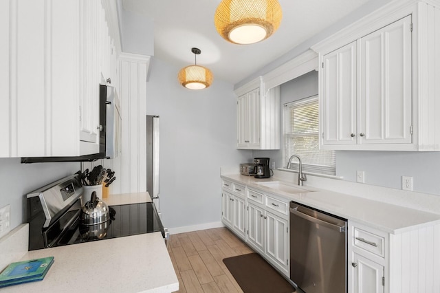 kitchen featuring a sink, white cabinets, hanging light fixtures, appliances with stainless steel finishes, and light countertops