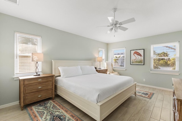 bedroom with ceiling fan, light wood finished floors, multiple windows, and baseboards