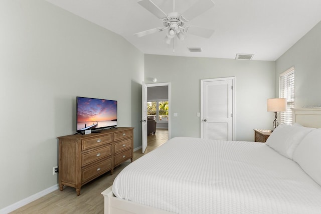 bedroom featuring ceiling fan, visible vents, baseboards, vaulted ceiling, and light wood-style floors