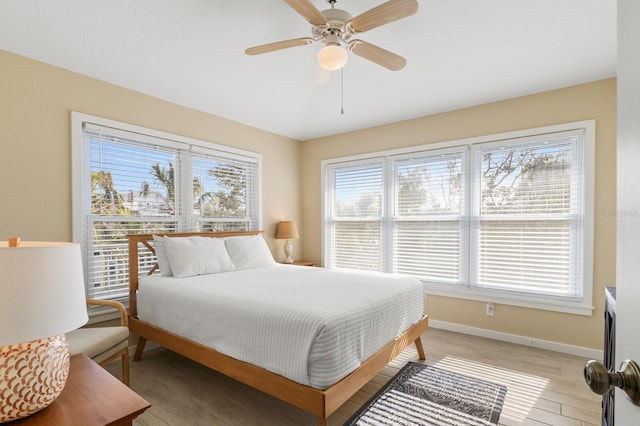 bedroom with light wood finished floors, baseboards, and a ceiling fan