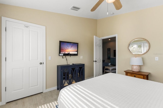 bedroom featuring baseboards, a ceiling fan, visible vents, and light wood-style floors