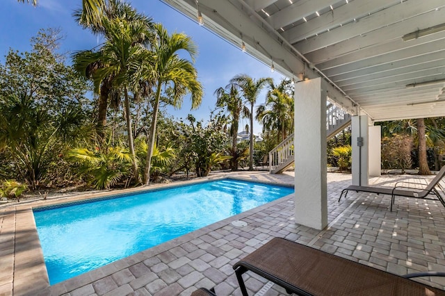 outdoor pool with a patio and stairs