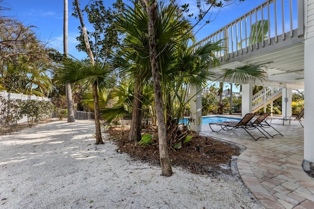 view of yard with stairs, a patio, fence, and an outdoor pool