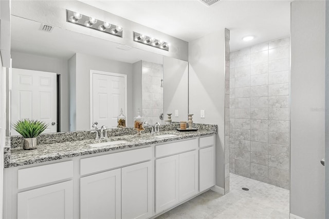 full bath featuring double vanity, visible vents, walk in shower, and a sink