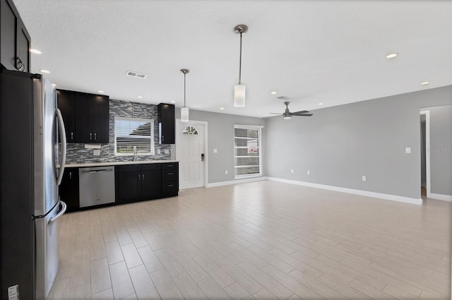 kitchen with sink, hanging light fixtures, stainless steel appliances, tasteful backsplash, and light hardwood / wood-style floors