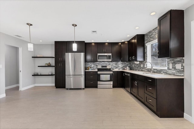 kitchen with pendant lighting, appliances with stainless steel finishes, sink, and dark brown cabinets