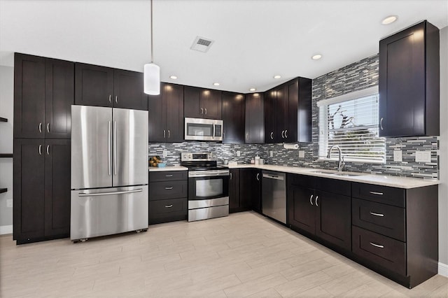 kitchen featuring sink, decorative light fixtures, dark brown cabinets, stainless steel appliances, and backsplash