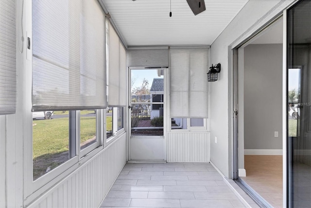 unfurnished sunroom featuring ceiling fan and a healthy amount of sunlight