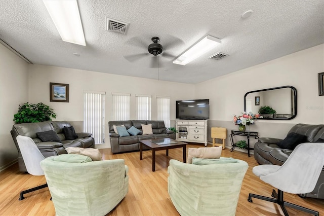 living room featuring ceiling fan, a textured ceiling, and light hardwood / wood-style floors