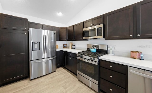 kitchen featuring appliances with stainless steel finishes, dark brown cabinets, light hardwood / wood-style flooring, and lofted ceiling