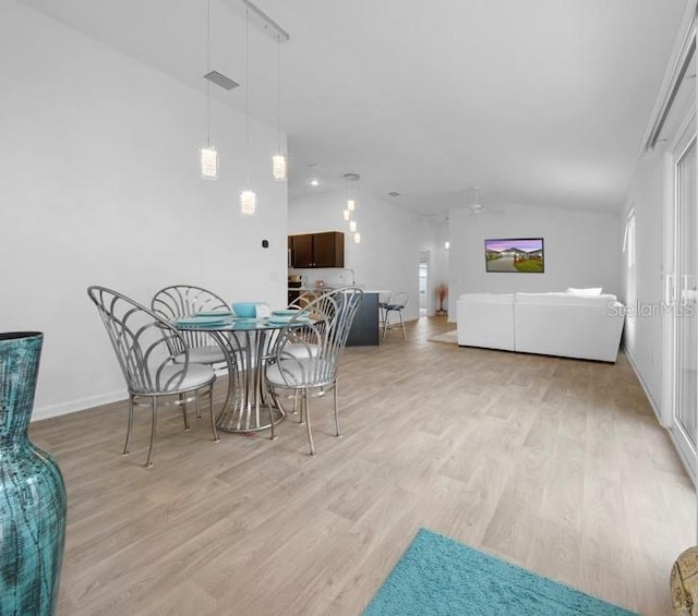 dining space with light wood-type flooring, vaulted ceiling, and ceiling fan