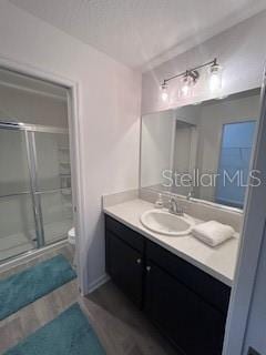 bathroom with toilet, an enclosed shower, and vanity