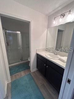 bathroom with toilet, hardwood / wood-style flooring, an enclosed shower, and vanity