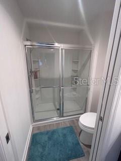 bathroom featuring toilet and a shower with shower door