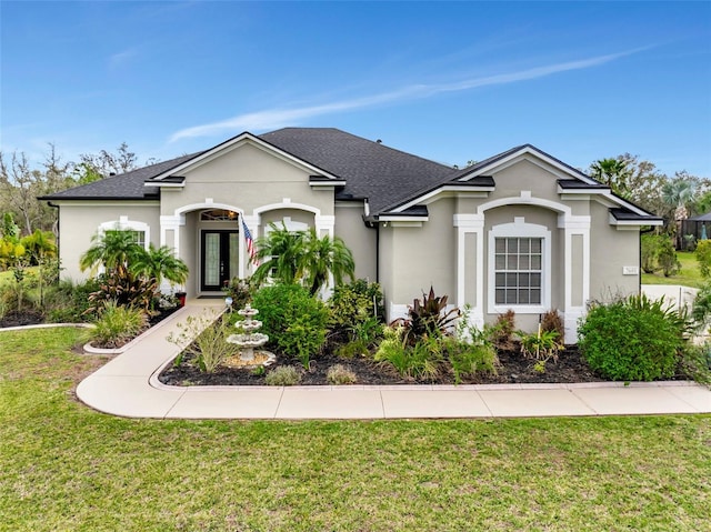 ranch-style home with a front lawn, a shingled roof, and stucco siding