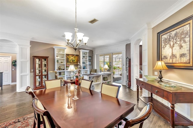 dining area featuring arched walkways, wood finished floors, visible vents, and crown molding