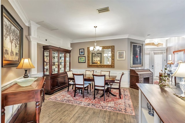 dining space with a wainscoted wall, plenty of natural light, visible vents, and wood finished floors