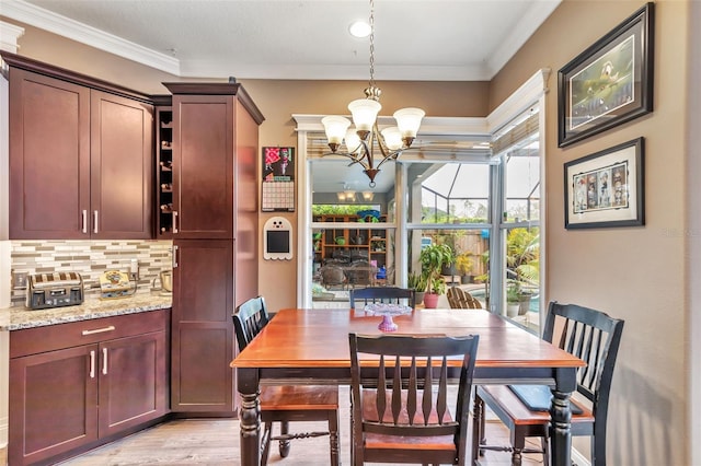 dining space with a chandelier, crown molding, and light wood-style flooring