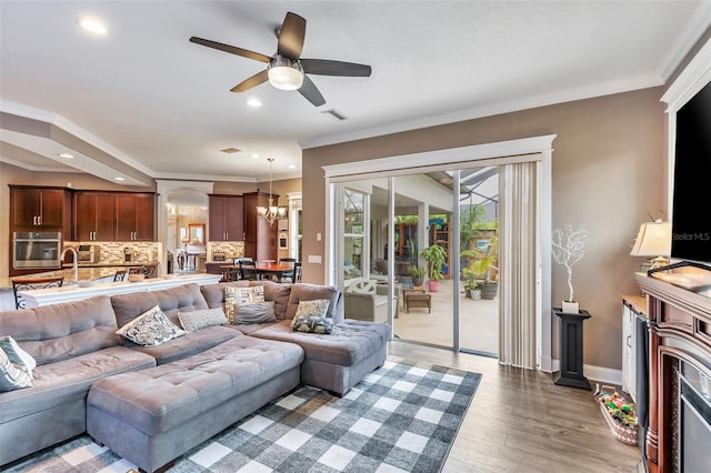 living area with baseboards, visible vents, light wood-style flooring, crown molding, and recessed lighting