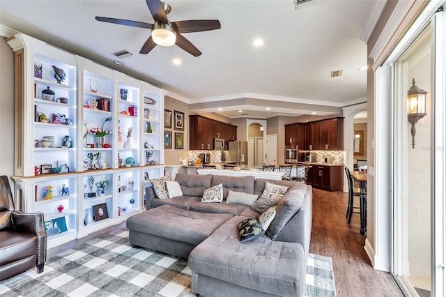 living room featuring arched walkways, visible vents, recessed lighting, and wood finished floors