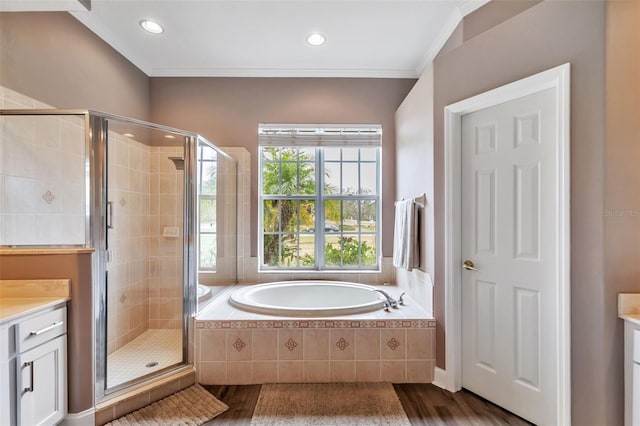 full bathroom with a garden tub, wood finished floors, vanity, ornamental molding, and a stall shower