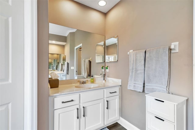 bathroom featuring ensuite bath, baseboards, and vanity