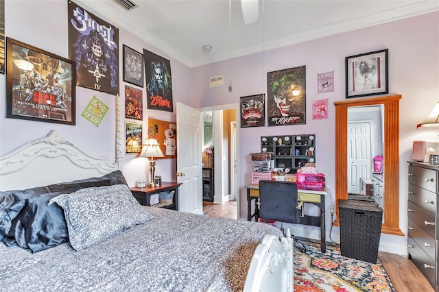 bedroom featuring light wood-style floors, visible vents, and crown molding