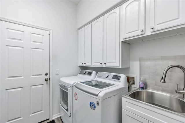 laundry room with cabinet space, a sink, and washing machine and clothes dryer