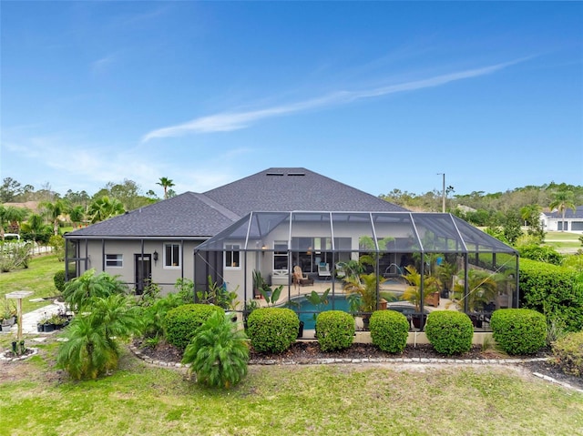 back of property with an outdoor pool, a lanai, roof with shingles, and a yard