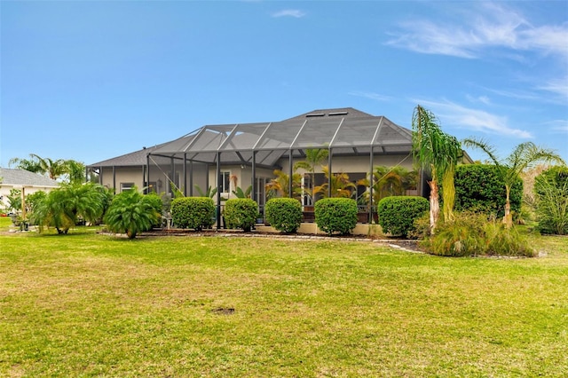 back of property featuring glass enclosure and a yard