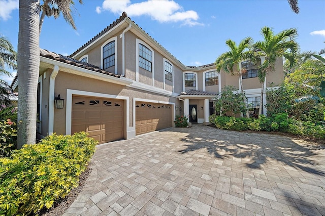 view of front of home featuring a garage, a tiled roof, decorative driveway, and stucco siding