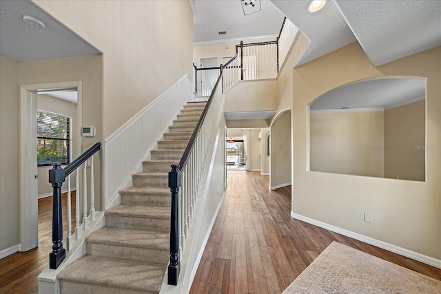 stairway featuring hardwood / wood-style floors, a high ceiling, and baseboards