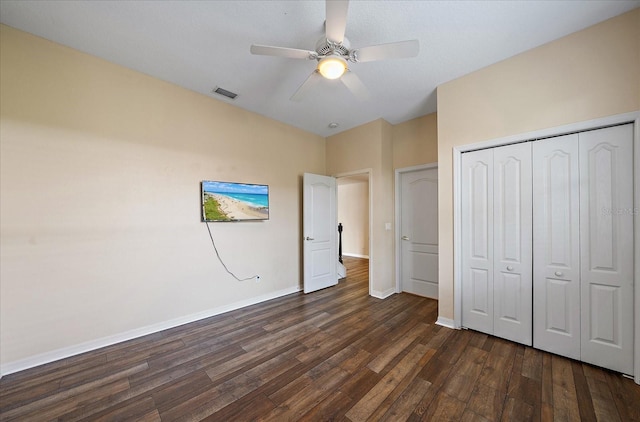 unfurnished bedroom with a closet, dark wood-style flooring, visible vents, and baseboards