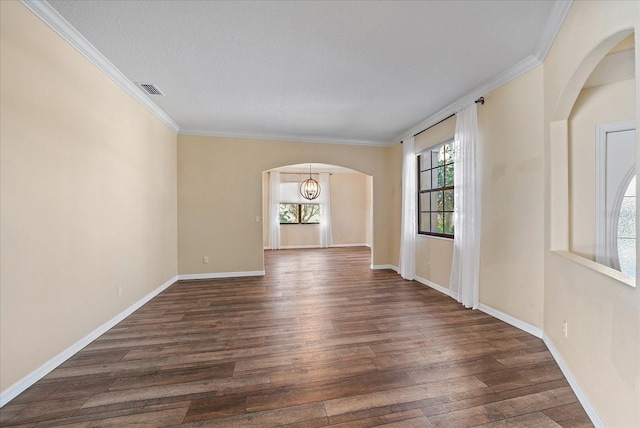 spare room featuring ornamental molding, arched walkways, dark wood-style flooring, and baseboards