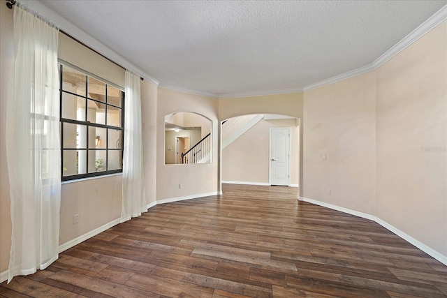 unfurnished room featuring a textured ceiling, arched walkways, wood finished floors, and ornamental molding