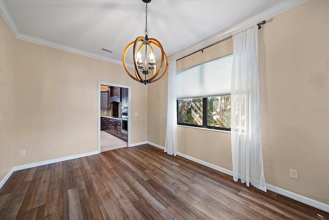 spare room featuring crown molding, a notable chandelier, visible vents, hardwood / wood-style floors, and baseboards