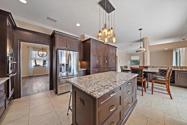 kitchen with visible vents, light stone counters, pendant lighting, crown molding, and stainless steel refrigerator with ice dispenser