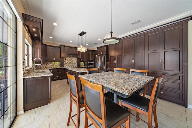 kitchen with a center island, decorative backsplash, freestanding refrigerator, a sink, and dark brown cabinets