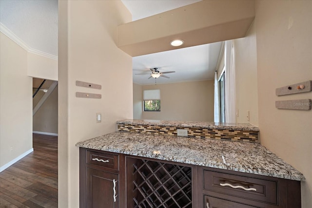 kitchen featuring tasteful backsplash, dark brown cabinets, ornamental molding, and light stone countertops