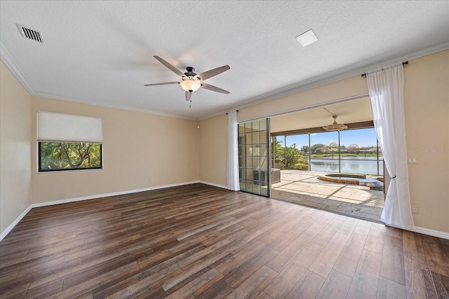 empty room with a water view, a ceiling fan, visible vents, and wood finished floors