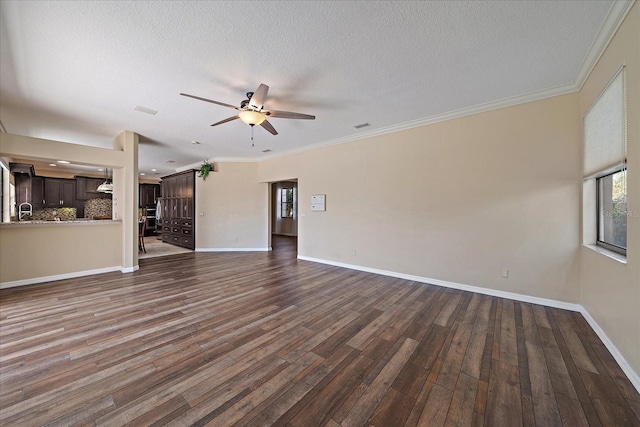 unfurnished living room with ceiling fan, a textured ceiling, dark wood-type flooring, baseboards, and crown molding